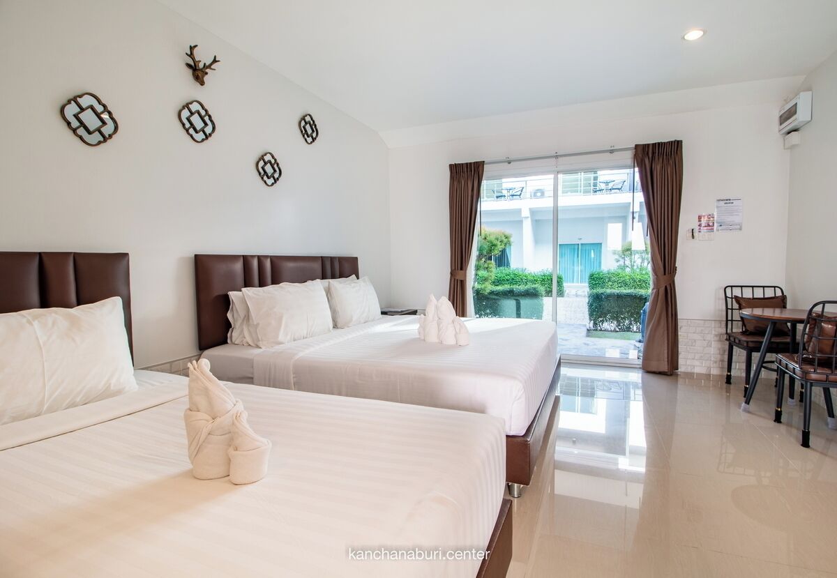 A hotel room with two beds, a dining area, and a view of the outside.