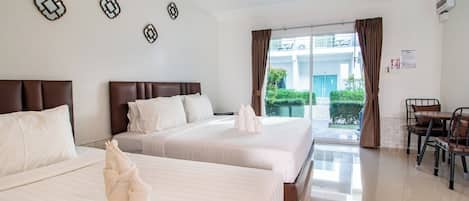 A hotel room with two beds, a dining area, and a view of the outside.