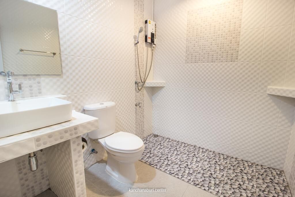 Une salle de bain avec un lavabo, des toilettes et une douche, le tout de couleur blanche.