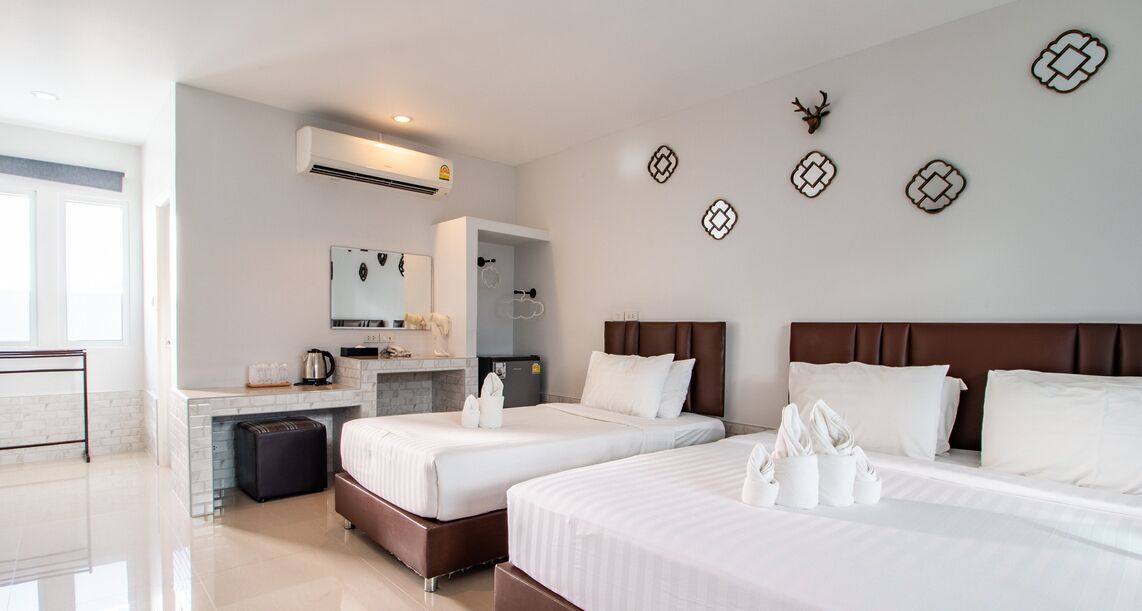 A hotel room with two beds, a desk, a mirror, and a minibar.
