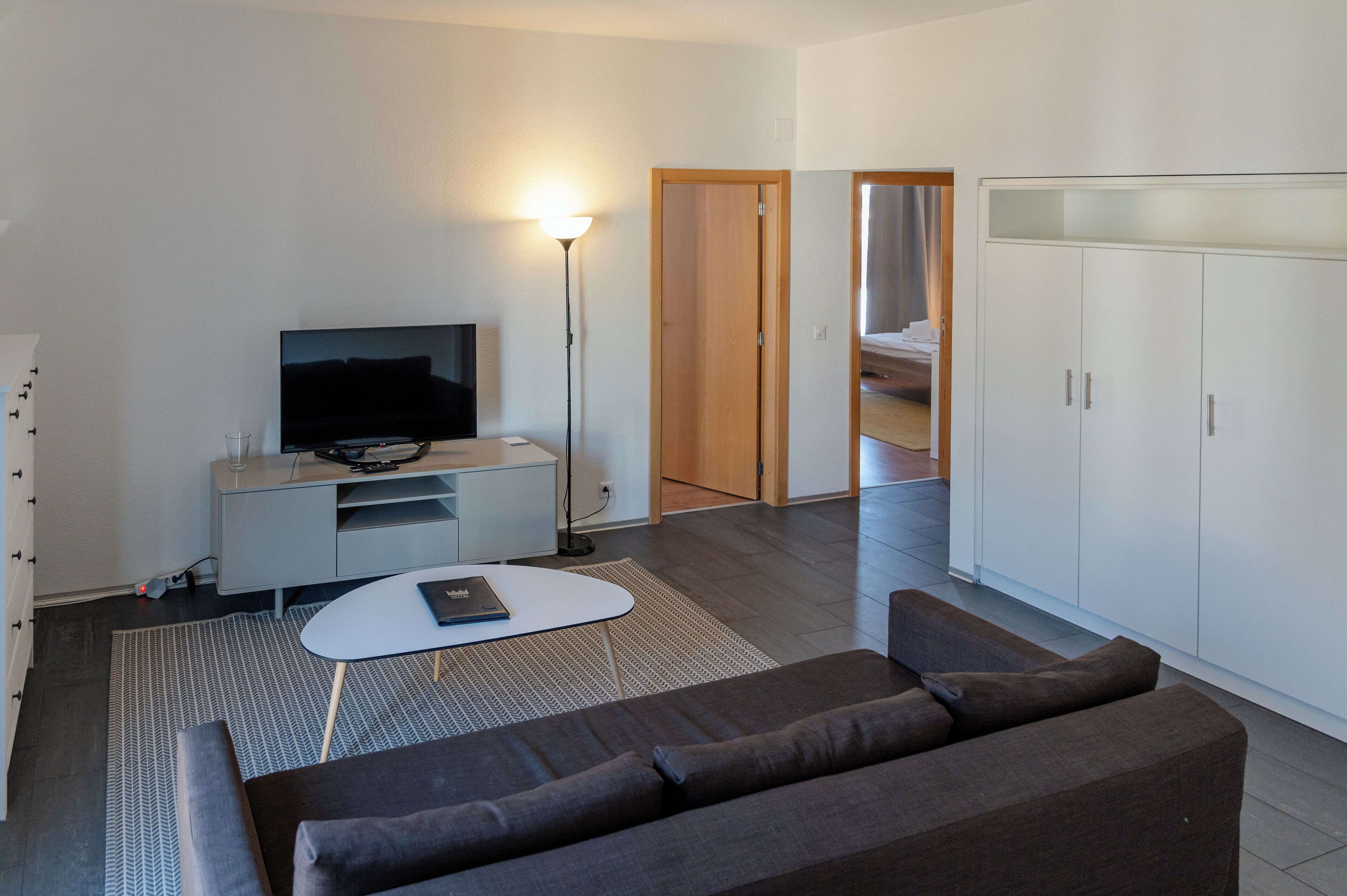 A modern living room with a sofa, a coffee table, a TV, and a wardrobe.
