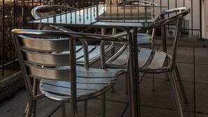 A metal table and chairs on a balcony with a view of snow-capped mountains and a building with red windows. - Los Lorentes Residences - Bulle (Bulle)