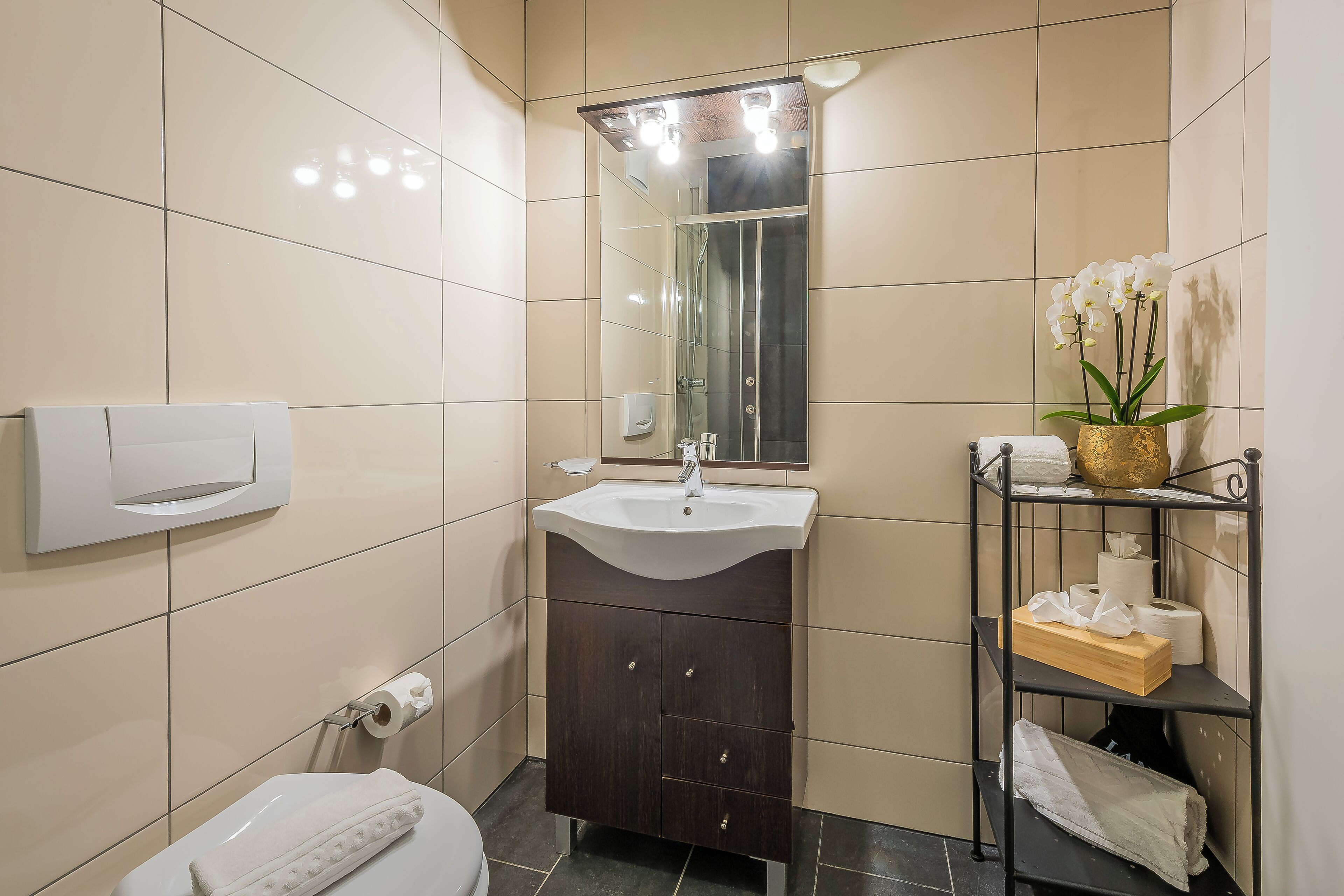 A bathroom with a white sink, dark wooden cabinet, and a shelf with toiletries.