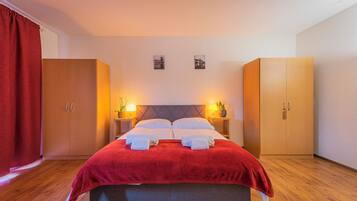 Ein ordentlich bezogenes Bett mit roter Decke, zwei Nachttischlampen und Holzschränken.