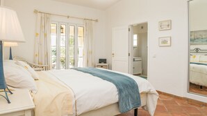 A bedroom with a bed, bedside table, lamp, and a window with curtains. - Bandicoot Villa, Lagoa de Momprolé, Algarve (Loulé)