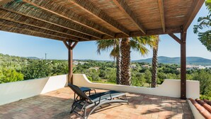 A covered outdoor area with a view of a green landscape, including trees and hills. - Bandicoot Villa, Lagoa de Momprolé, Algarve (Loulé)