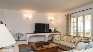 A living room with a TV, sofa, coffee table, and decorative items. - Bandicoot Villa, Lagoa de Momprolé, Algarve (Loulé)