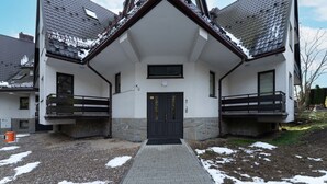 A modern building with a central entrance, two balconies, and a stone facade.