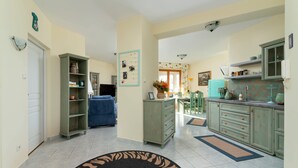 A spacious living area with a blue sofa, a kitchen with green cabinets, and a dining area with a table and chairs.