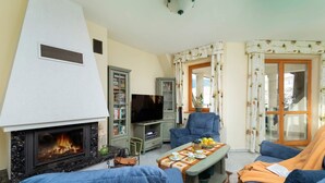 A cozy living room with a fireplace, blue sofas, a television, and a bookshelf.