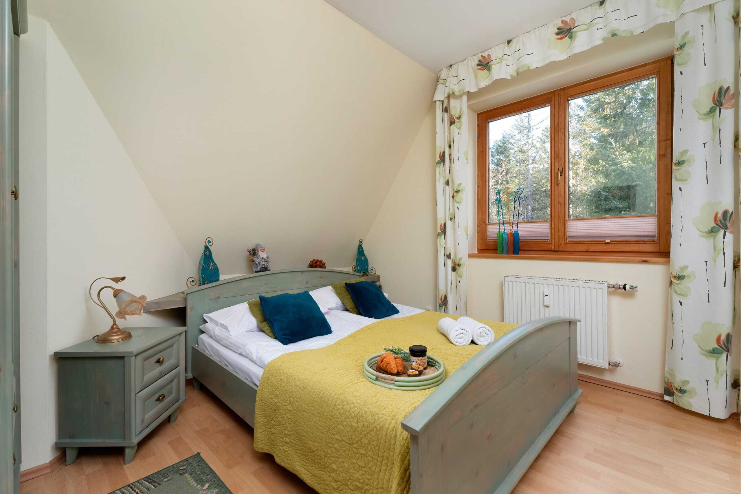 Een slaapkamer met een bed, nachtkastje, raam met gordijnen en een radiator.