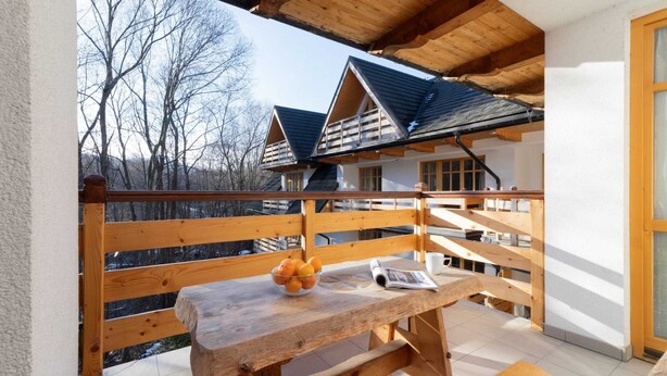 A wooden balcony with a table, a bowl of fruit, and a newspaper. - Stylish Apartment in Zakopane | Balcony | Close to Krupówki Street (Zakopane)