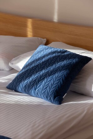 Una cama con un almohadón azul acolchado y un cabecero de madera.