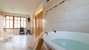 A spa area with a large bathtub, wooden chairs, and a view of the outside through large windows. - Stylish Apartment in Zakopane | Balcony | Close to Krupówki Street (Zakopane)