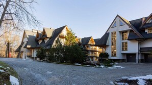 A residential area with houses featuring steep roofs and large windows, a cobblestone driveway, and a tree in the foreground. - Stylish Apartment in Zakopane | Balcony | Close to Krupówki Street (Zakopane)
