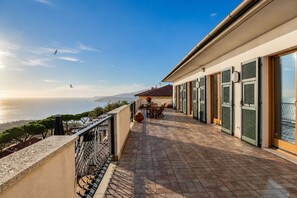 Ein Balkon mit Meerblick, einem Tisch mit Stühlen und einem Geländer.
