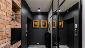 Un baño moderno con pared de ladrillo, un lavabo negro y tres máscaras doradas enmarcadas en la pared.