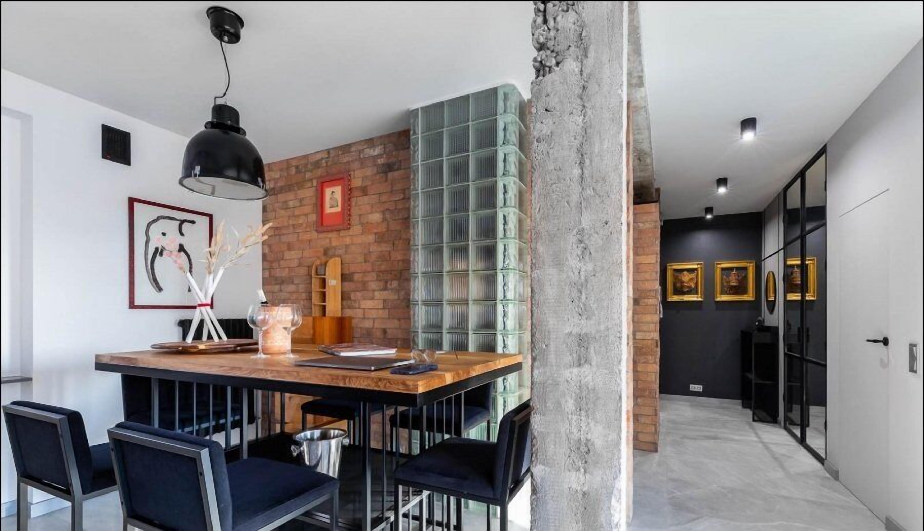 A modern dining area with a brick wall, a wooden table, and black chairs.