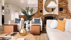 Ein modernes Wohnzimmer mit Kamin aus Backsteinen, weißen Sofas und einem runden Tisch mit Dekorationselementen.
