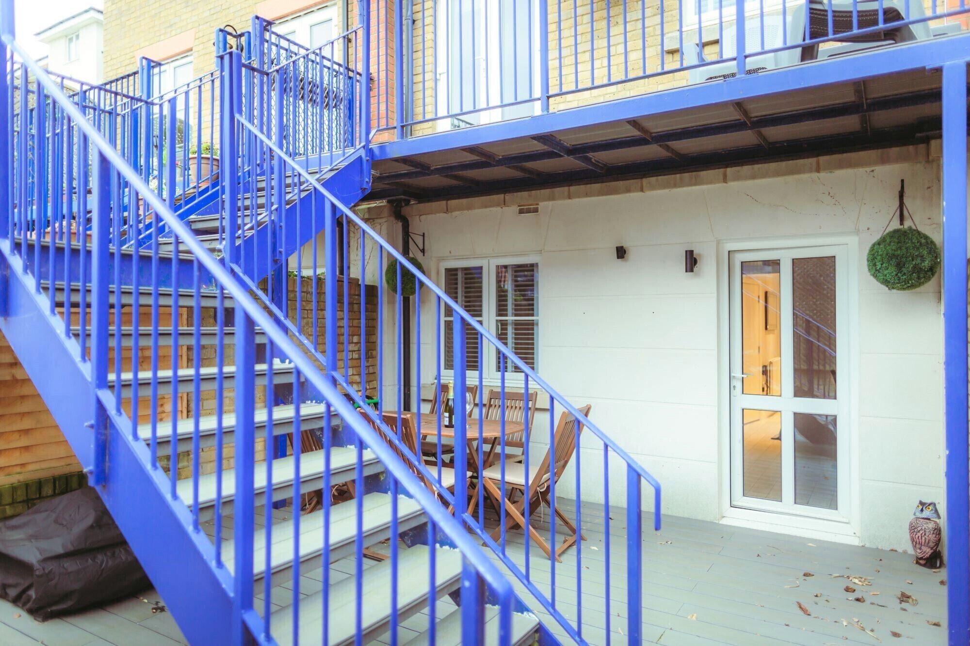 A blue metal staircase leading to a wooden deck with outdoor furniture.