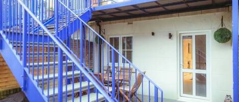 A blue metal staircase leading to a wooden deck with outdoor furniture.