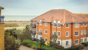 Un edificio a più piani in mattoni con tetto piatto, un balcone e vista sul mare.