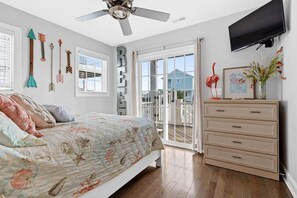 Une chambre à coucher avec un lit, une commode, une télévision et un balcon offrant une vue.