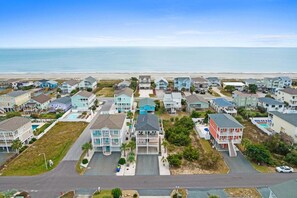 Une zone résidentielle côtière avec des maisons, une plage et un ciel dégagé.