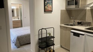 A compact kitchen with a microwave, sink, and dishwasher. There's a small shelf with dishes and a framed picture on the wall. - Vacation cottage with swimming pool in Saint-Rémy-de-Provence (Saint-Rémy-de-Provence)
