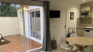 A modern living room with a sliding glass door leading to a patio, a dining area with a table and chairs, and a kitchenette with a microwave and dishwasher. - Vacation cottage with swimming pool in Saint-Rémy-de-Provence (Saint-Rémy-de-Provence)