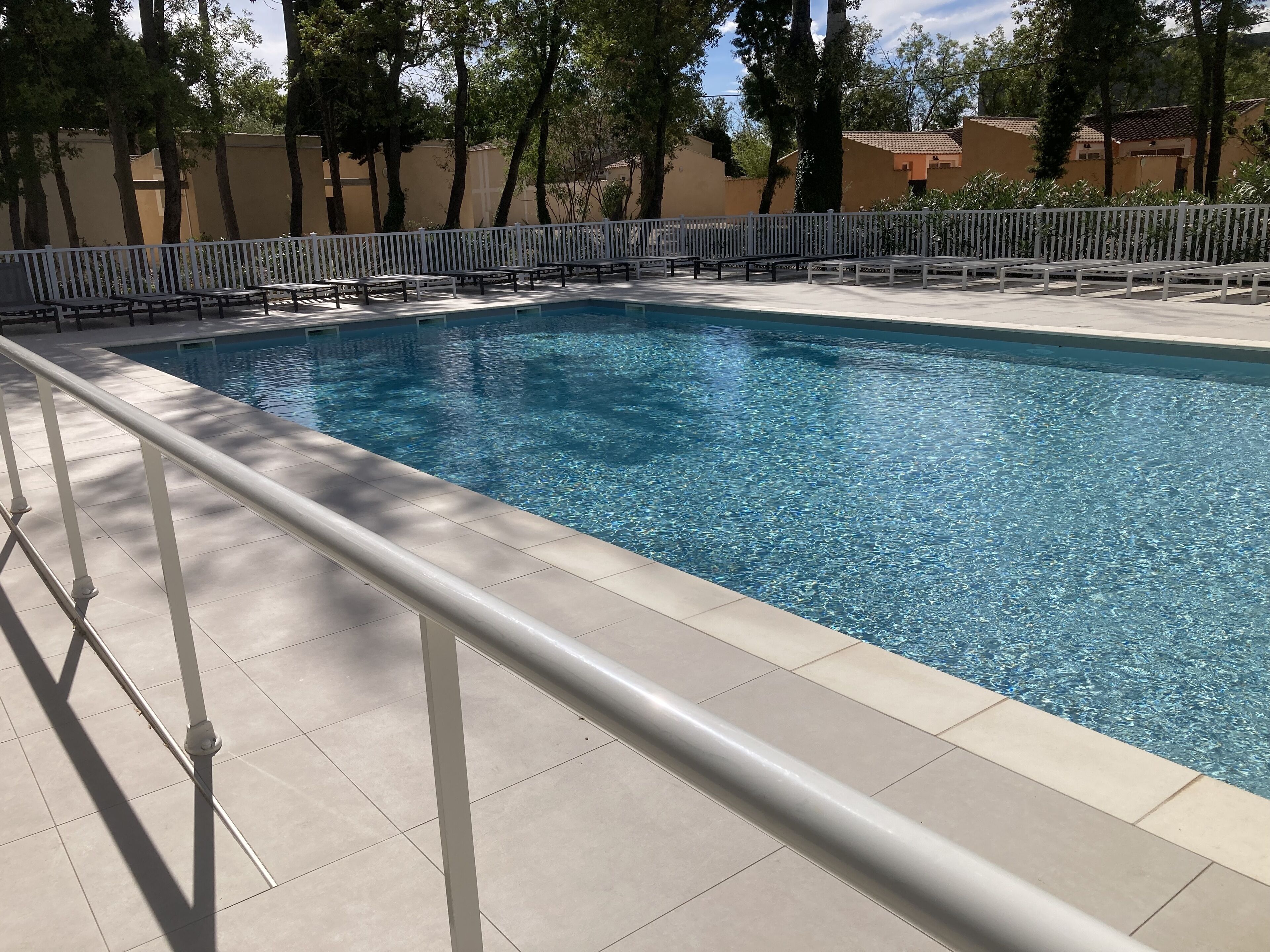 A swimming pool with a white fence and benches.