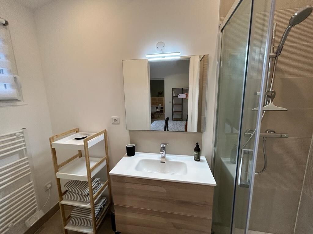 A bathroom with a white sink, mirror, and glass shower enclosure.