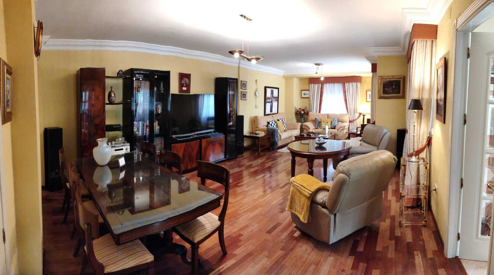 A spacious living room with a dining area, a sofa set, and a television.