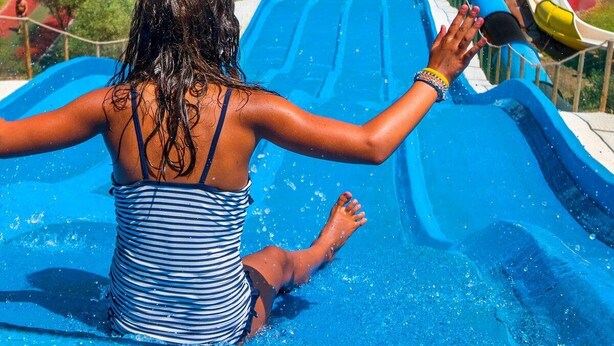 Une personne dévale une toboggan aquatique bleu dans un parc aquatique.