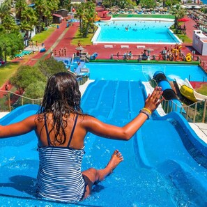 Uma pessoa deslizando num tobogã azul num parque aquático.