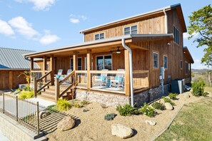 Ein zweistöckiges Holzhaus mit einer Veranda, einem Steinfundament und einer Schotterfläche.