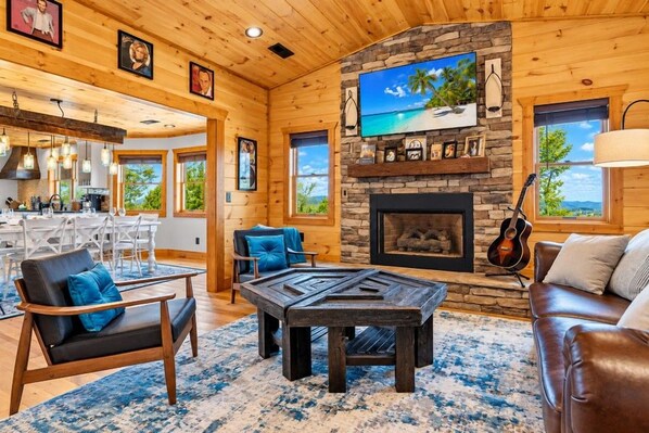 A cozy interior with a stone fireplace, wooden ceiling, and a view of the outdoors.