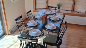 A dining area with a table set for four, surrounded by chairs, with a window and blinds in the background. - Private Canandaigua Retreat- Hot Tub/Pet Friendly (Canandaigua)