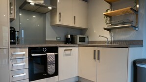 Una cocina moderna con armarios blancos, horno empotrado, microondas y cafetera.