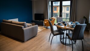 Una sala moderna con un sofá, una mesa de comedor para cuatro personas y un televisor.
