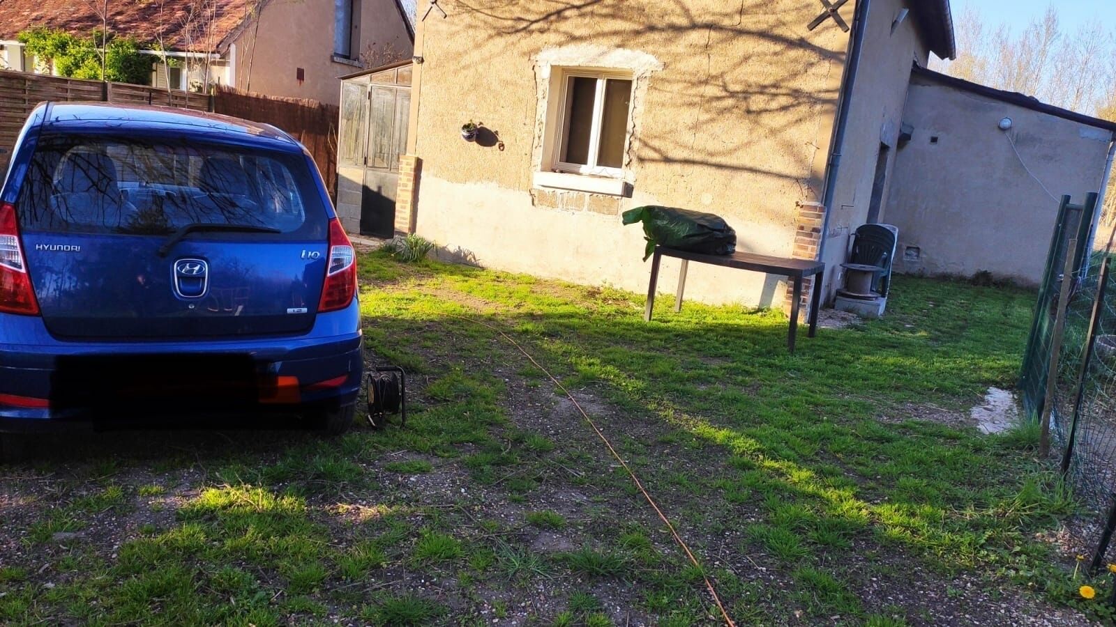 A blue Hyundai SUV parked in a grassy yard with a house in the background.