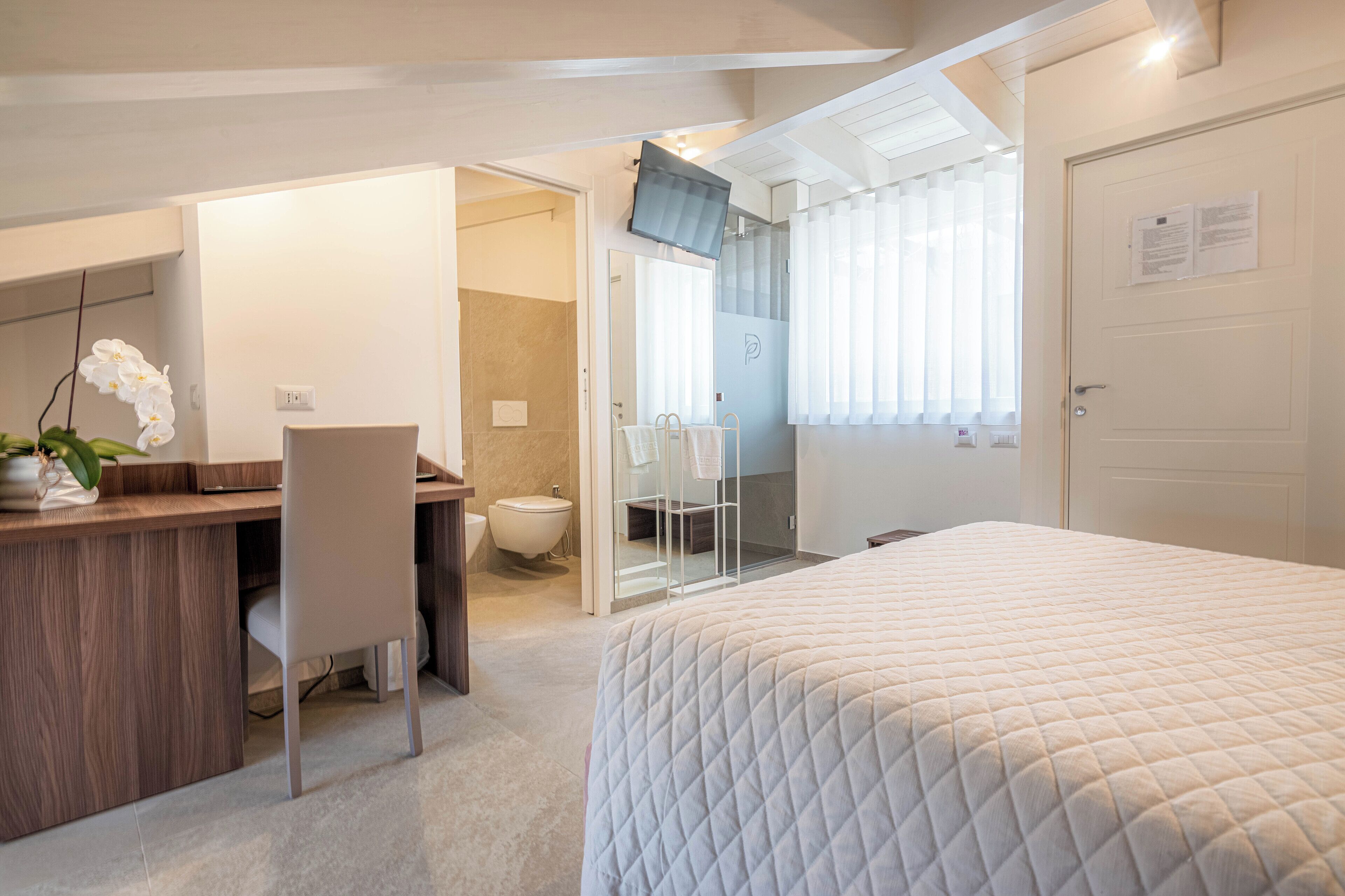 Una habitación de hotel moderna con cama, escritorio y zona de ducha.