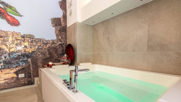Une salle de bain moderne avec une grande baignoire, un mur en pierre et un miroir décoratif.
