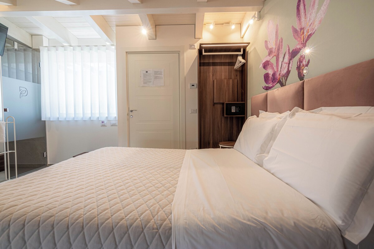 Une chambre d’hôtel avec un grand lit, une armoire en bois, une petite table et un téléviseur fixé au mur.