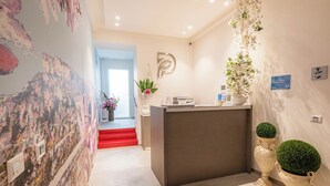 Un espace d’accueil au design moderne, comprenant un comptoir de réception, un panneau mural et des plantes décoratives.