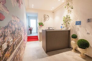Un'area reception dal design moderno, con una scrivania, una insegna a parete e piante ornamentali.