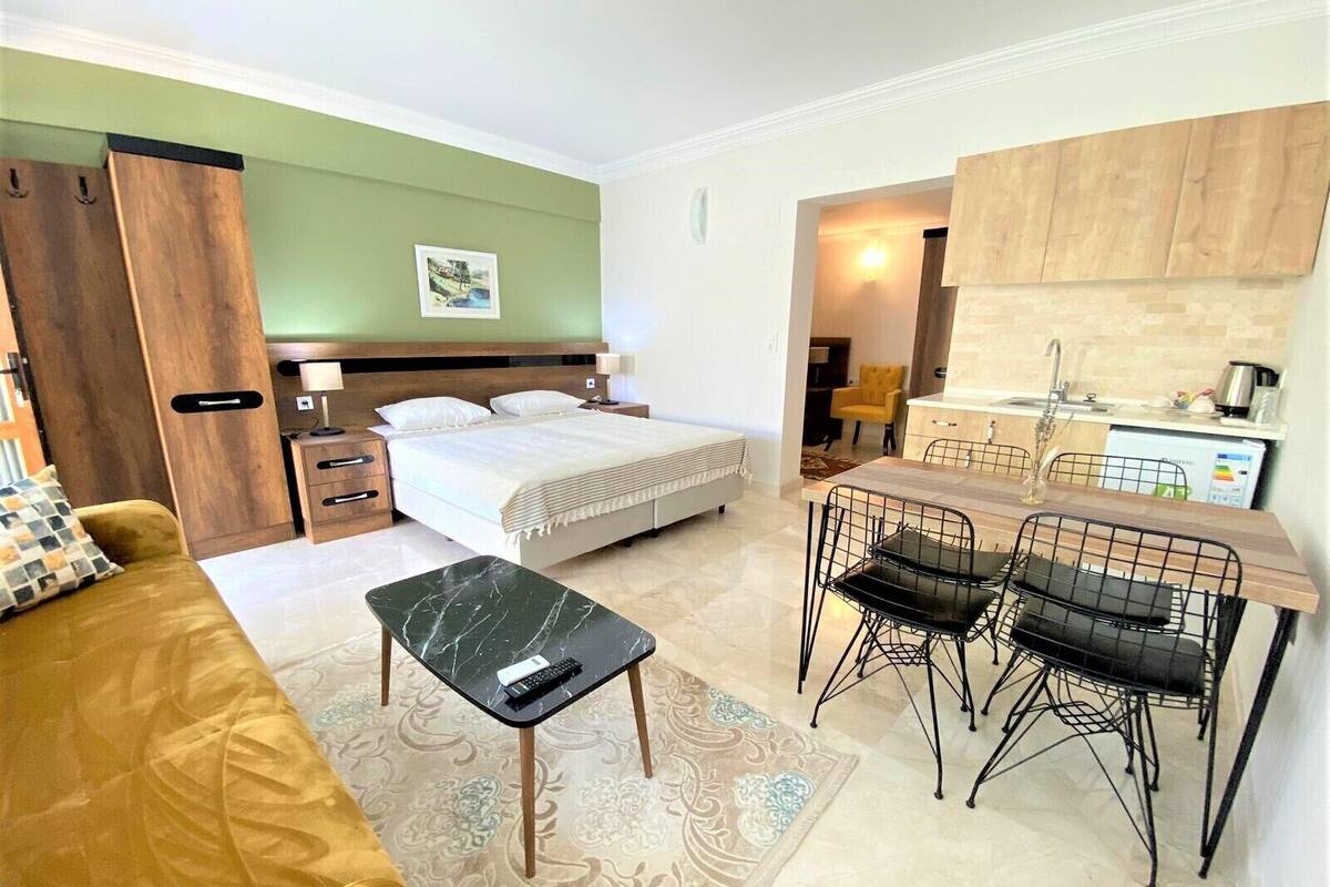 Camera d'albergo compatta con un letto, un comodino e una piccola zona pranzo con sedie e tavolo.