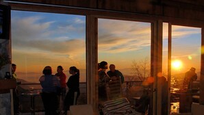 A group of people on a balcony overlooking a sunset with mountains in the distance. - Luxury chalet with best skiing in the South American Andes (farellones)