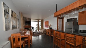 A modern kitchen with wooden cabinets, a dining area with a long table and chairs, and a bar area with stools. - Luxury chalet with best skiing in the South American Andes (farellones)