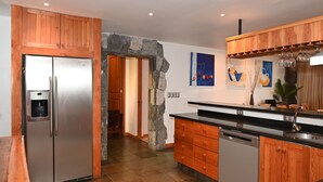 A kitchen with wooden cabinets, a stainless steel refrigerator, a dishwasher, and a stone archway.